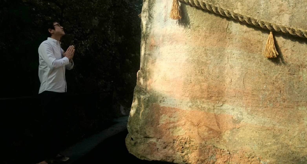 生石（おうしこ）神社の御神体の前で手を合わせる佐々木さん。