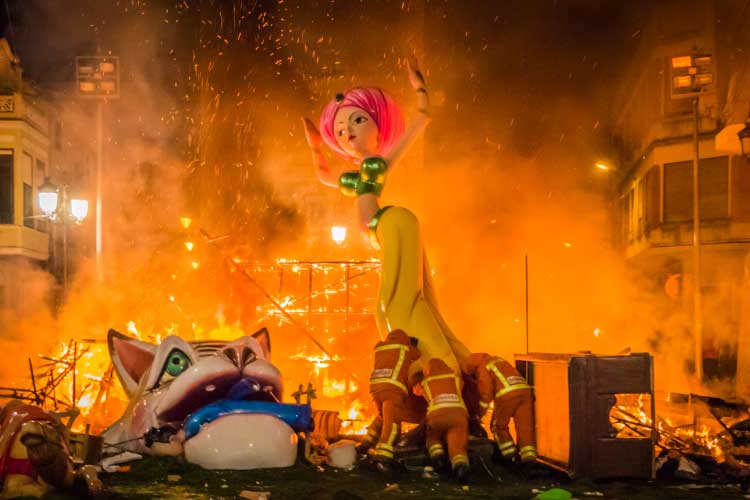 火に燃える人形の残りの部分を移動する消防士たちの様子